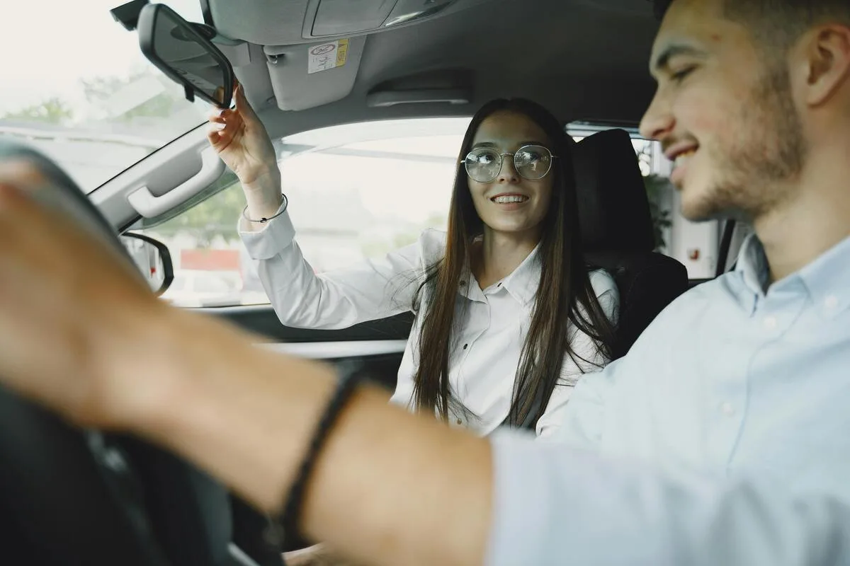 Mother supporting her teenage son as he learns to drive for the first time